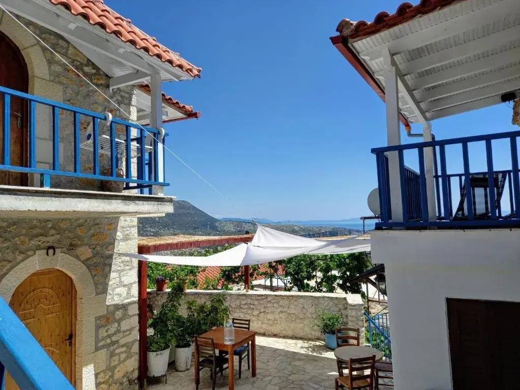 Stone buildings with blue balconies and a sea-view terrace at Amphora Guesthouse in Himara Old Town