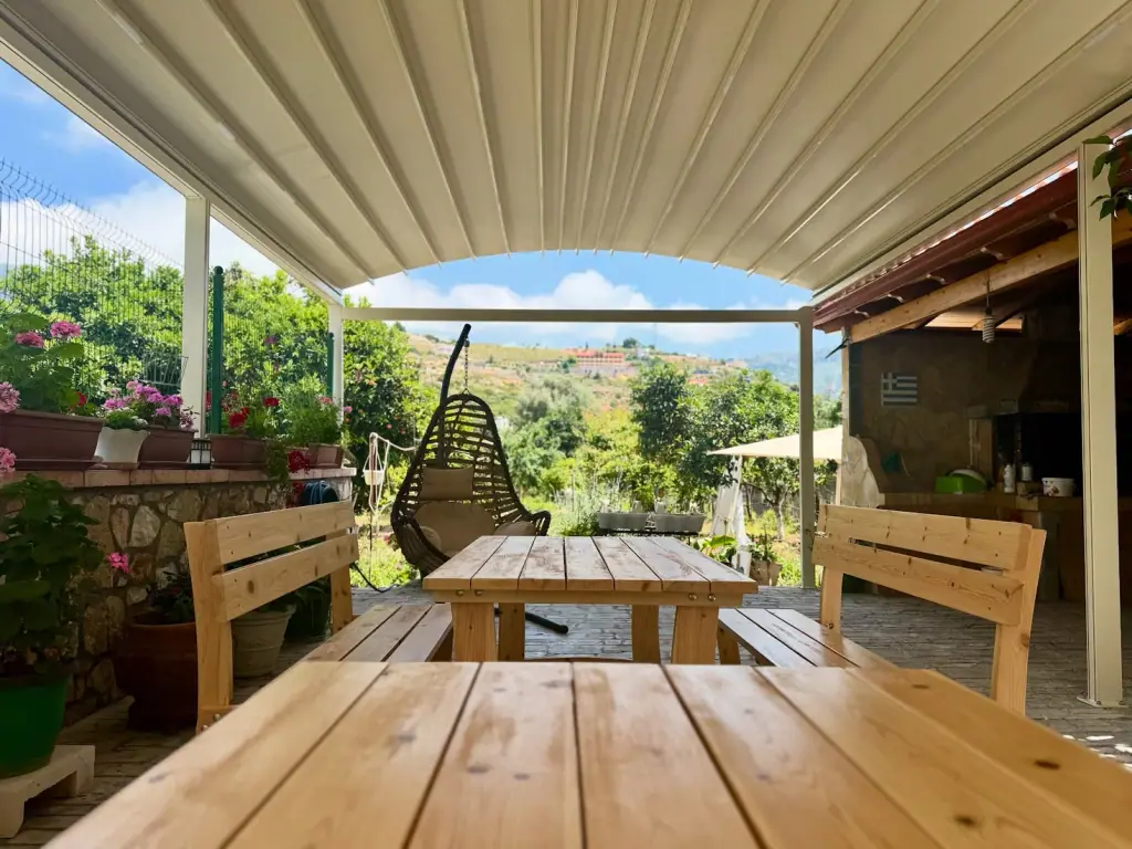 Covered wooden terrace with hanging chair and valley view at Elpis Guest House in Himara