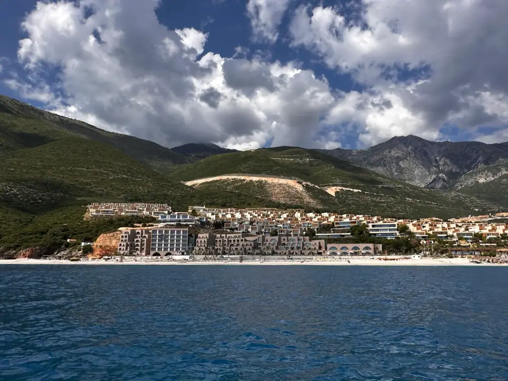 Green Coast development seen from the sea in Palasë, Albania, with the resort buildings and beach below the mountains