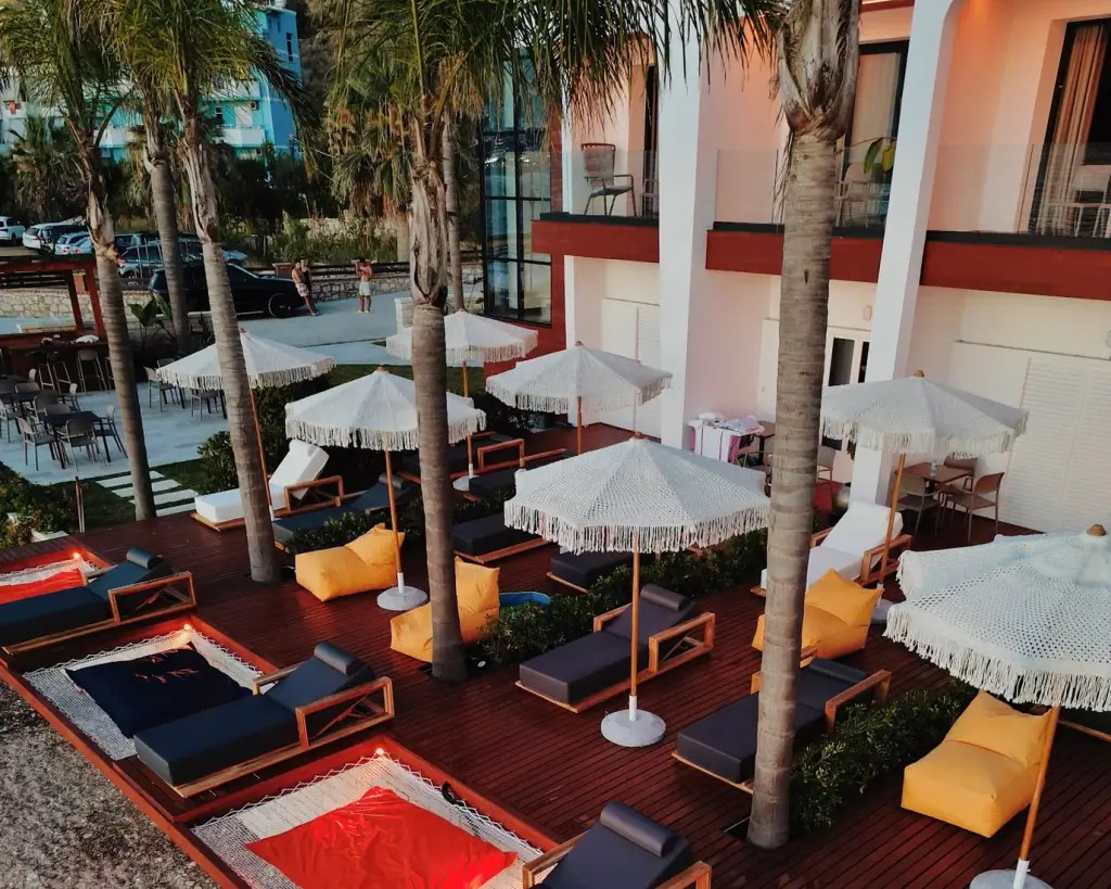 Macramé sun umbrellas and loungers on the beach deck at Oniro by Iliria Palace, Himare