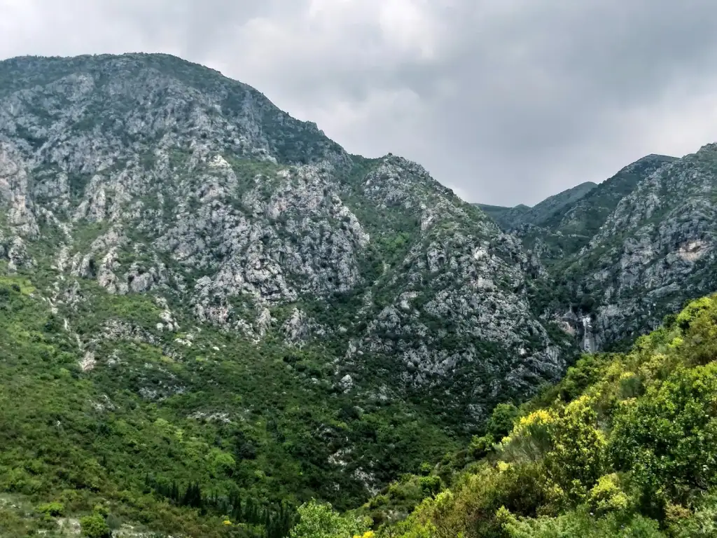 Vuno Waterfall cascading over mossy rocks into a turquoise pool in the wooded hills above the Albanian Riviera
