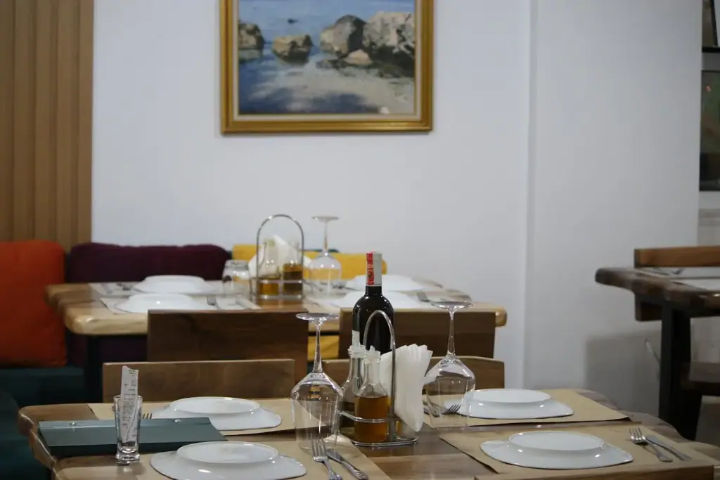 Marble-walled dining room with wooden tables and wine display at Arxontiko Restaurant in Himara
