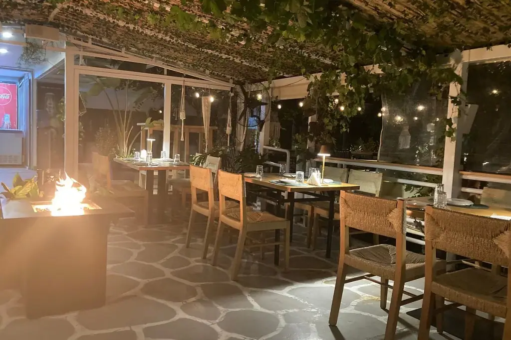 Set table on a wooden deck terrace with hillside and sea view at Fig and Olive Bistro in Himara