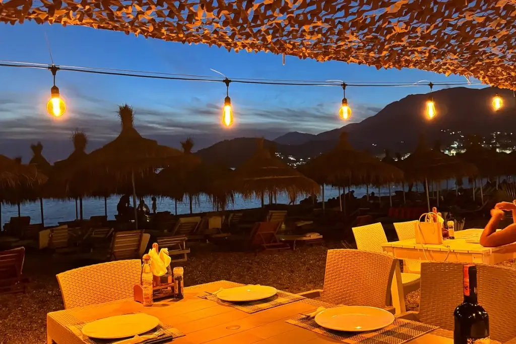 Wooden beachfront pergola with set tables at sunset at Lui Potam on Potam Beach in Himara