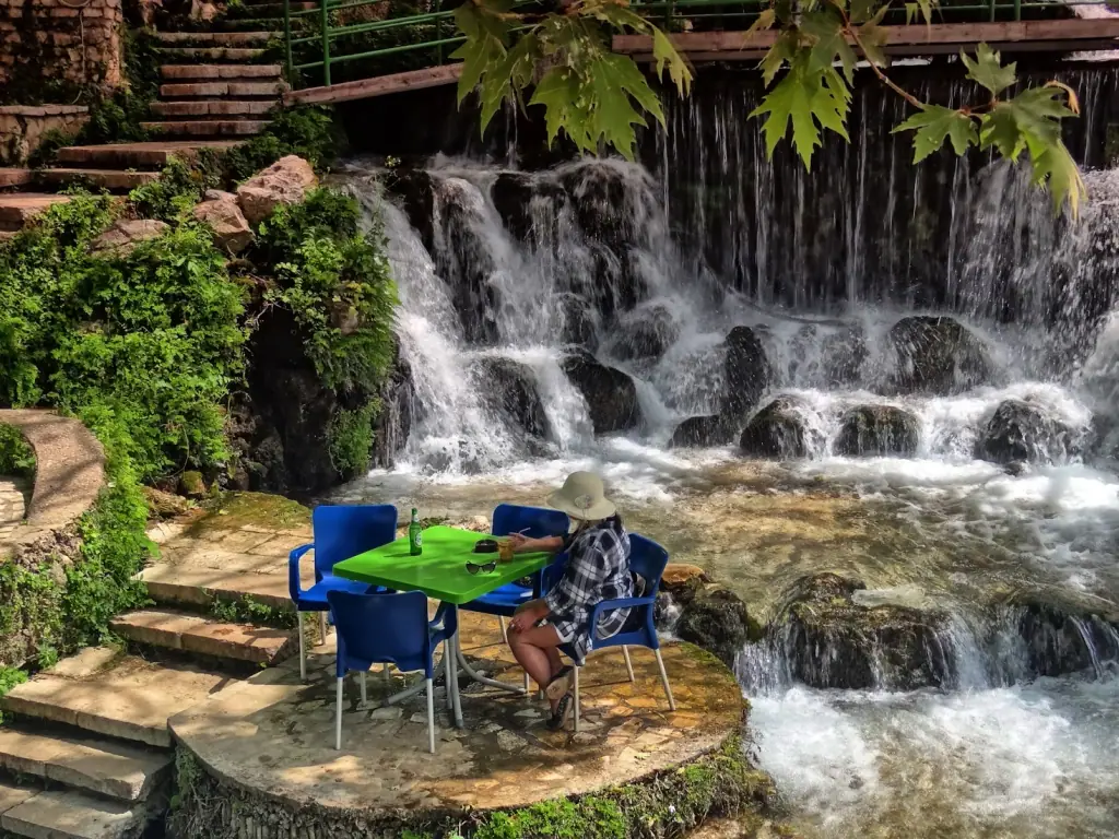 A table set on a stone platform beside the cascading Borsh Waterfall at Restaurant Ujvara