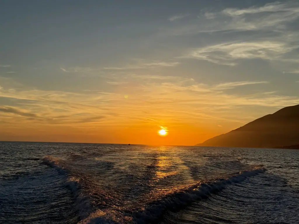 Boat on the Ionian Sea at golden hour during a Himara sunset cruise, Albanian Riviera