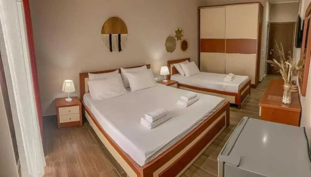 A room at Kleanthi's Hotel with a double bed, a single bed, a wardrobe and a wall-mounted television