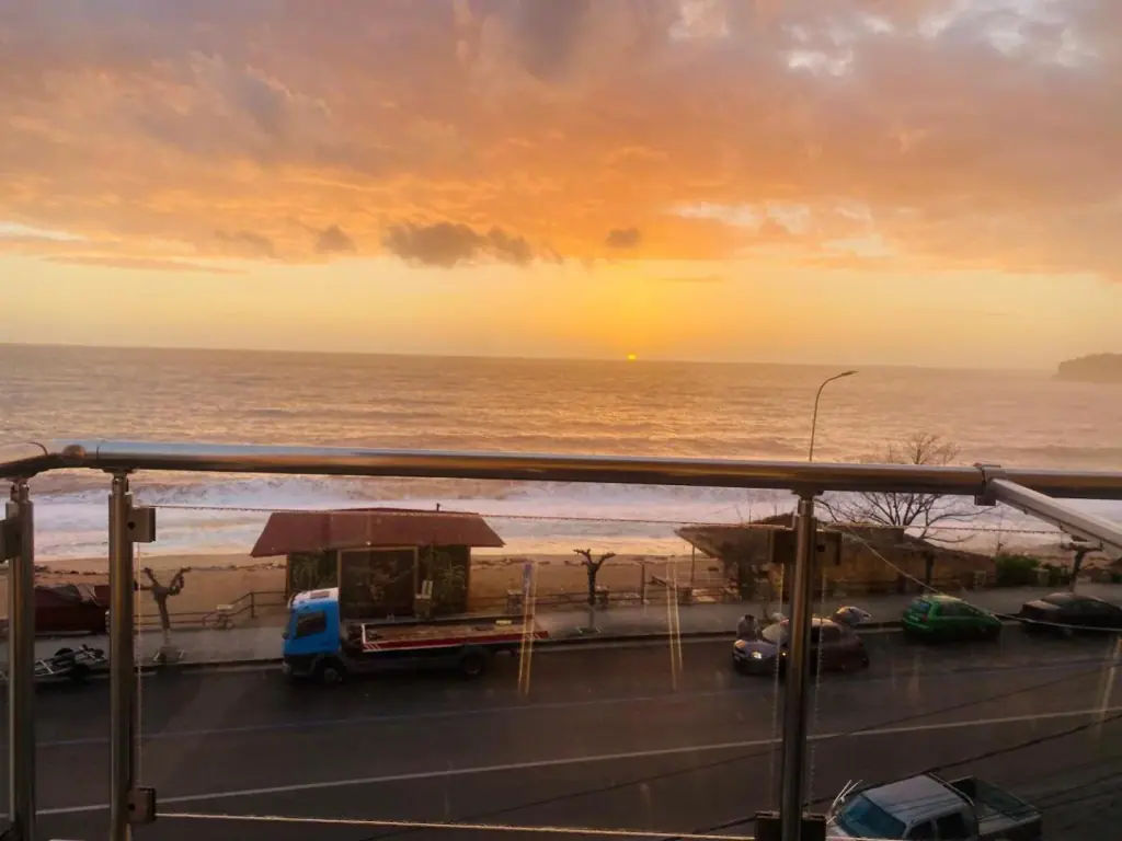 Sunset over the sea seen from a balcony at Kleanthi's Hotel, with the coast road below