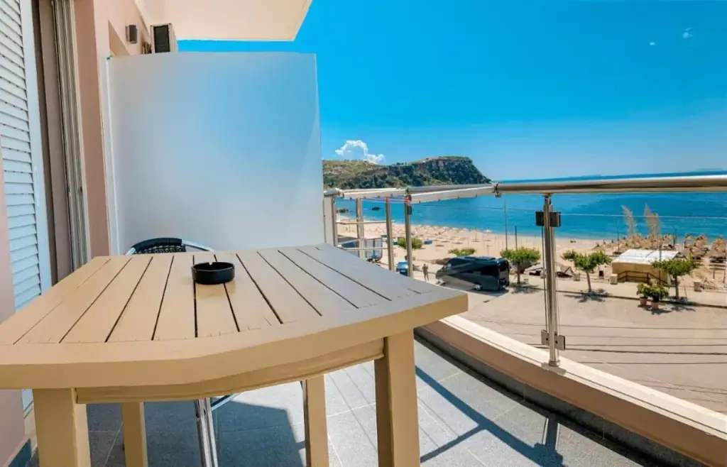 A balcony table and glass-panelled rail at Kleanthi's Hotel looking over Prinos Beach and the sea