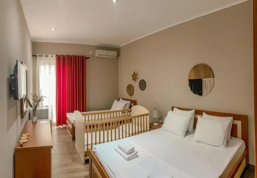 A family room at Kleanthi's Hotel with a double bed, a single bed and a wooden cot