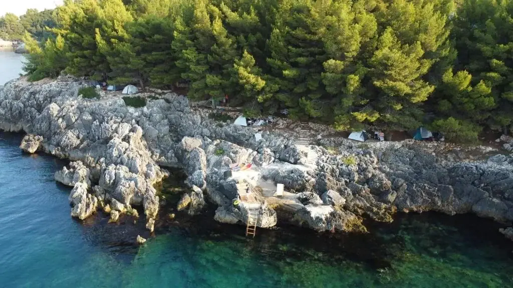 A steel swimming ladder dropping from the limestone ledge into clear green water
