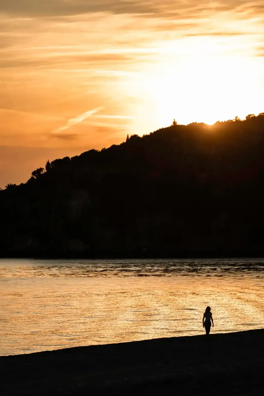 The sun going down behind the headland at Livadhi, the water gone gold and a single figure on the dark shore