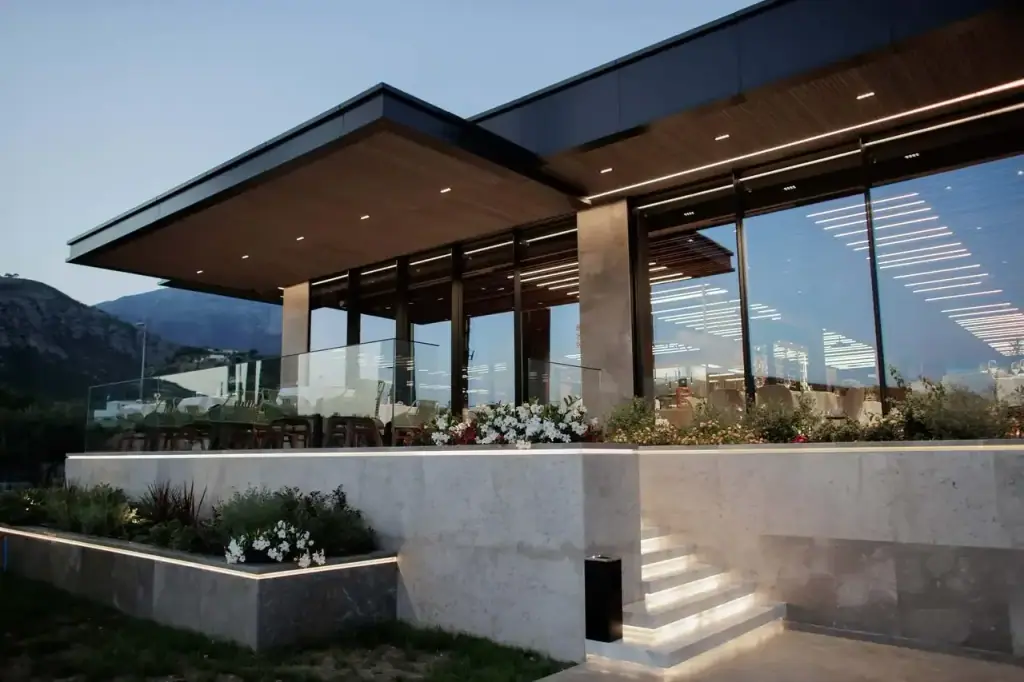 The glazed restaurant pavilion at Prado seen from outside in daylight, the mountains behind it