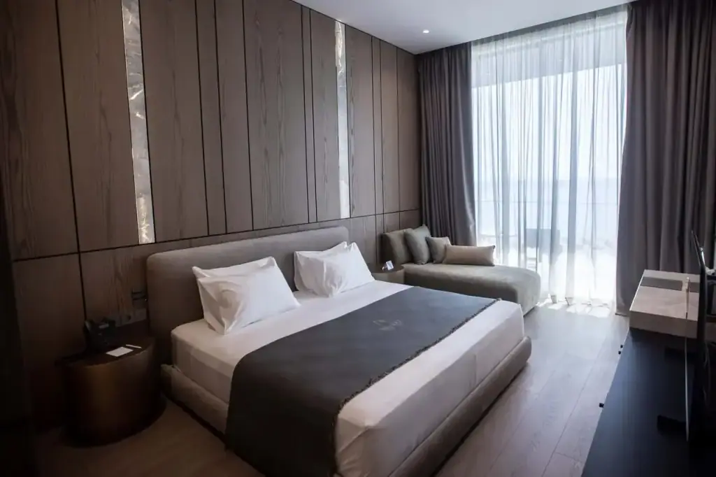 A Junior Suite with a sea view at Prado, the bed facing sliding doors onto the balcony