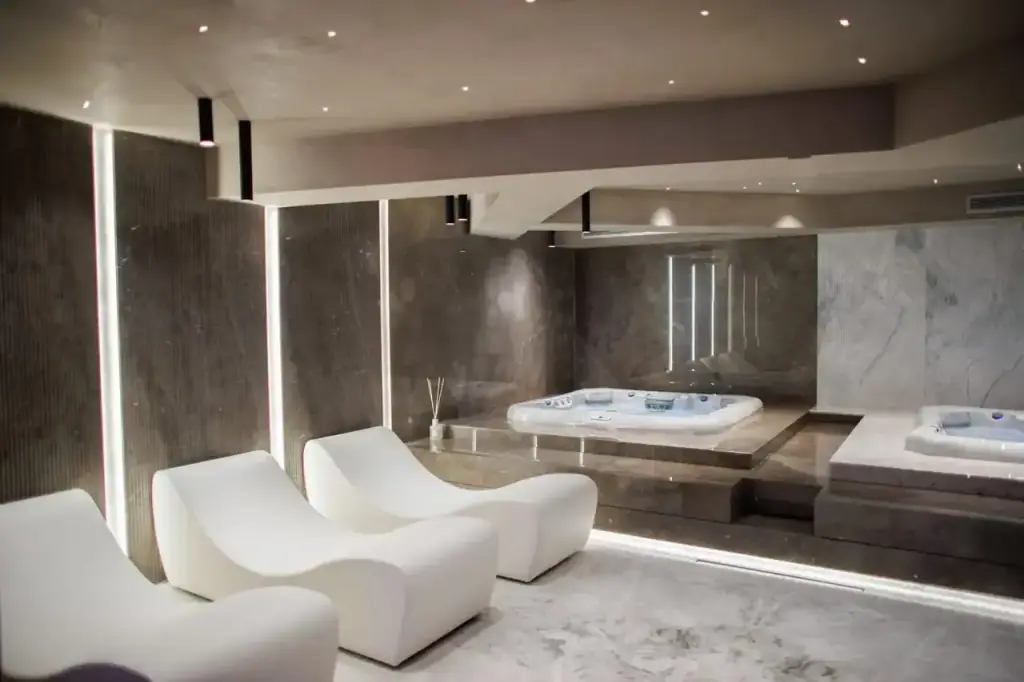 The jacuzzi room at Prado in dark marble with moulded white loungers beside it
