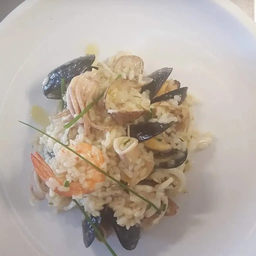A plate of seafood risotto with mussels, prawns and squid, finished with chives
