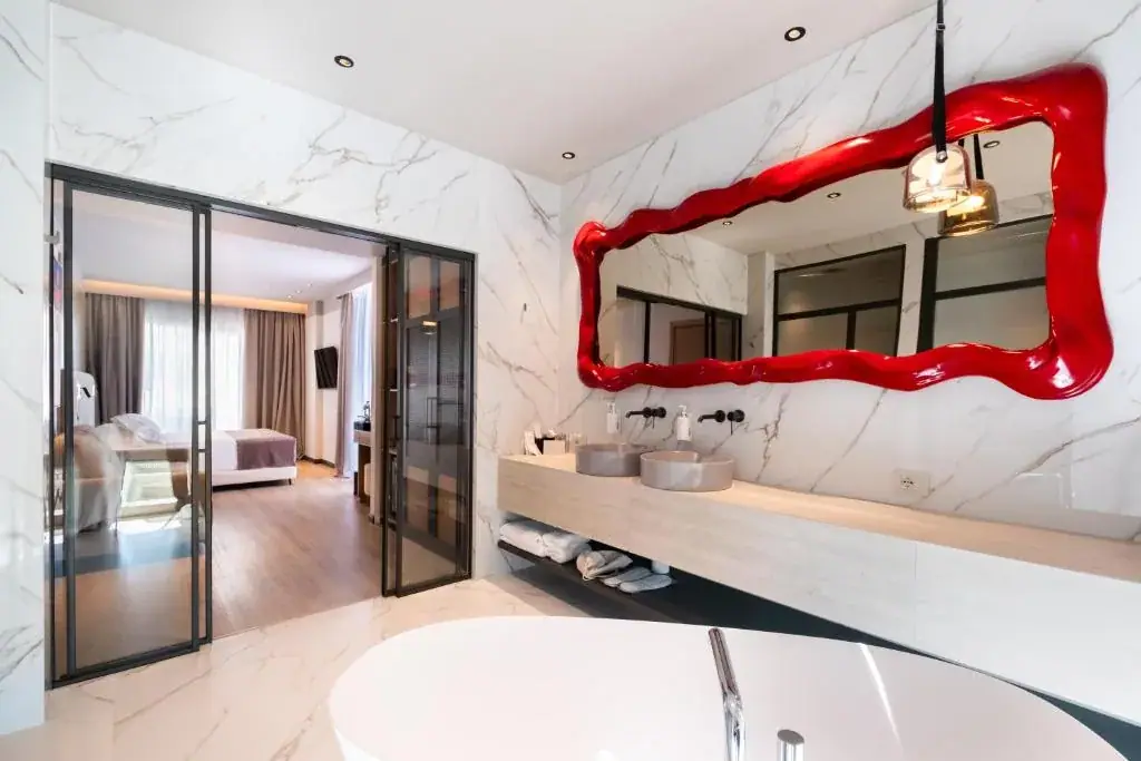 The freestanding bath in the Junior Suite with bath tub, with the sculpted red mirror