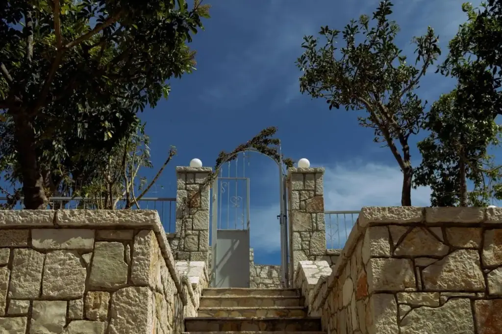 A white metal gate between two stone pillars at the top of the steps