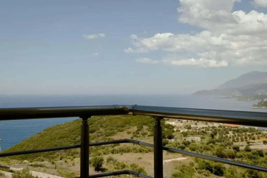 The view from a balcony rail across the wooded headland to the sea