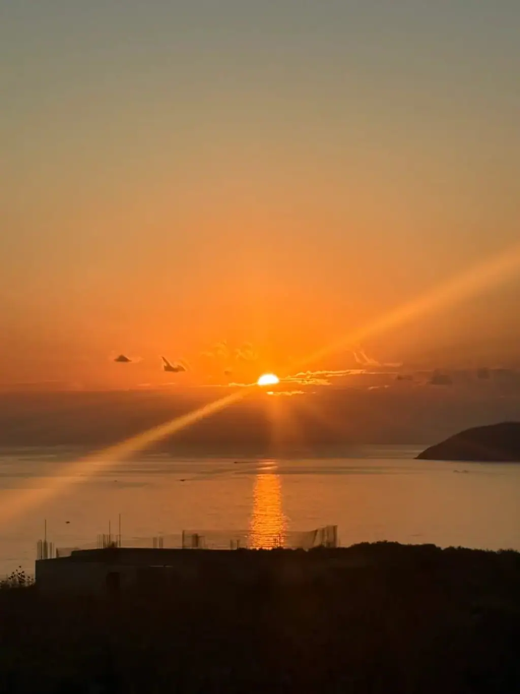 The sun going down into the open Ionian, rays fanning across the water