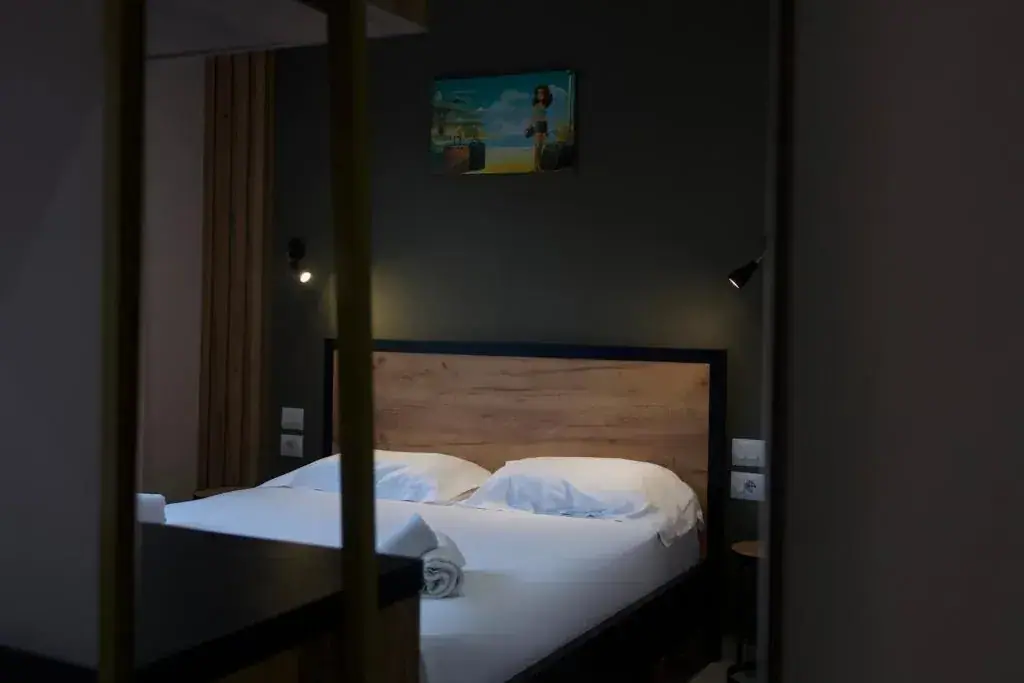 A double bed with an oak headboard against a charcoal wall under a framed seaside print