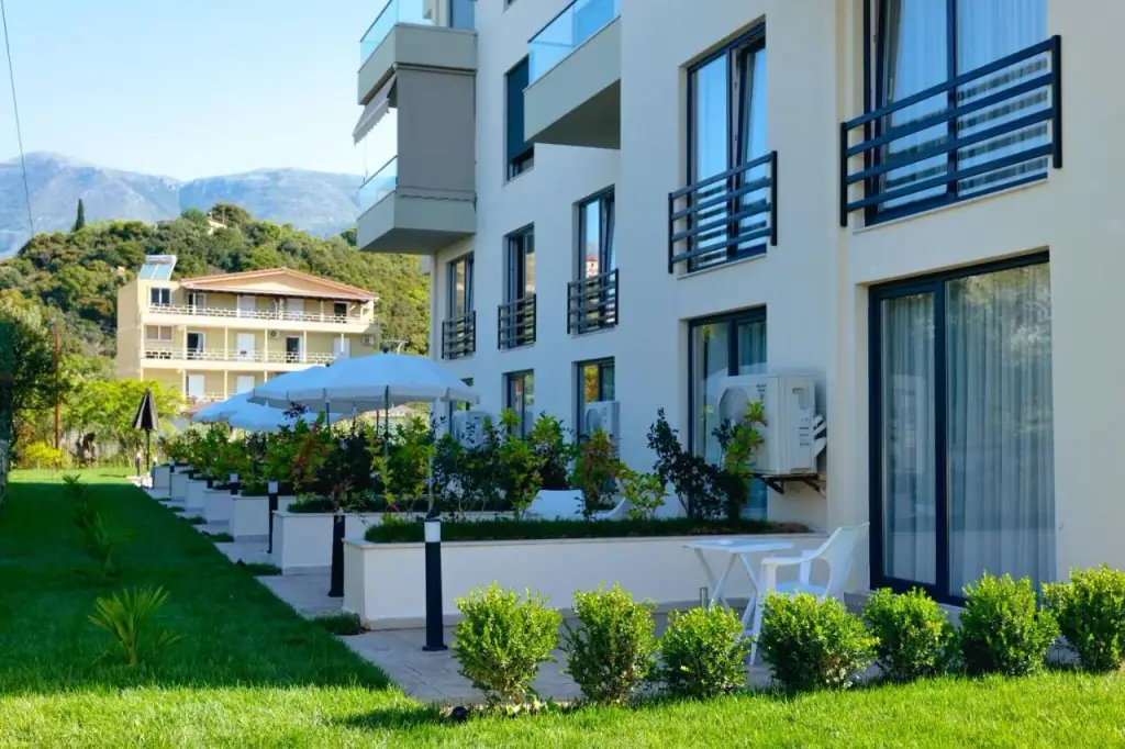 The garden elevation of the hotel with balconies, two parasols over the terrace and the hills behind
