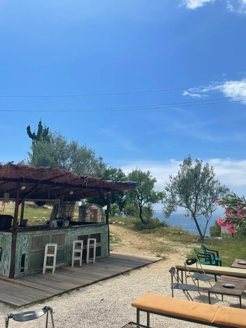 The bar's timber deck and benches with olive trees and the Ionian sea beyond
