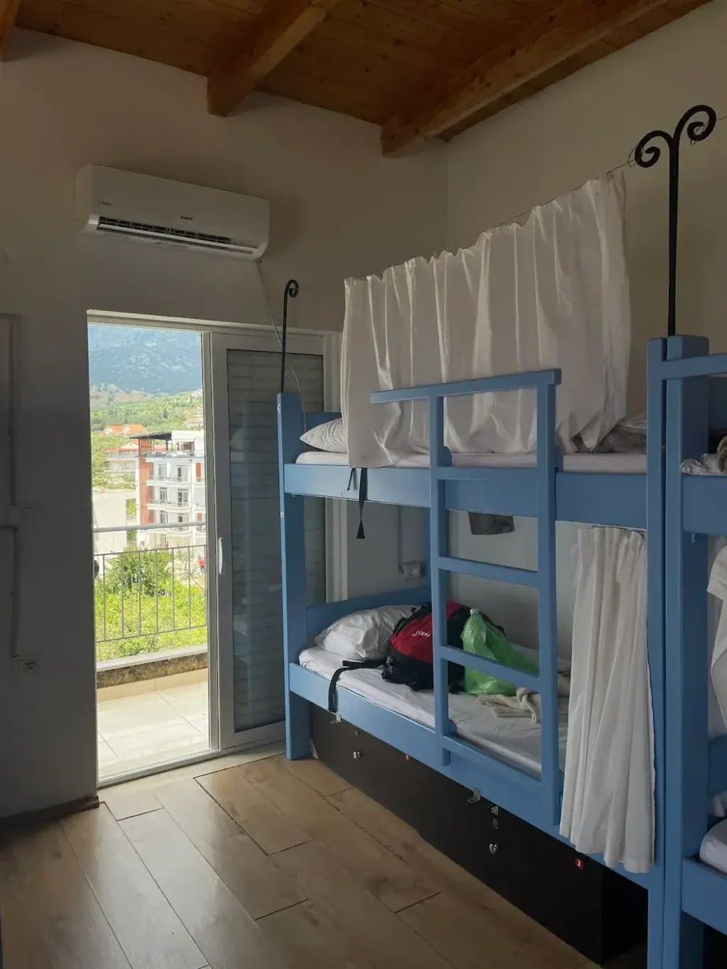 Blue bunk beds under a timber ceiling beside an open balcony door, Trip'n'Hostel Seaside
