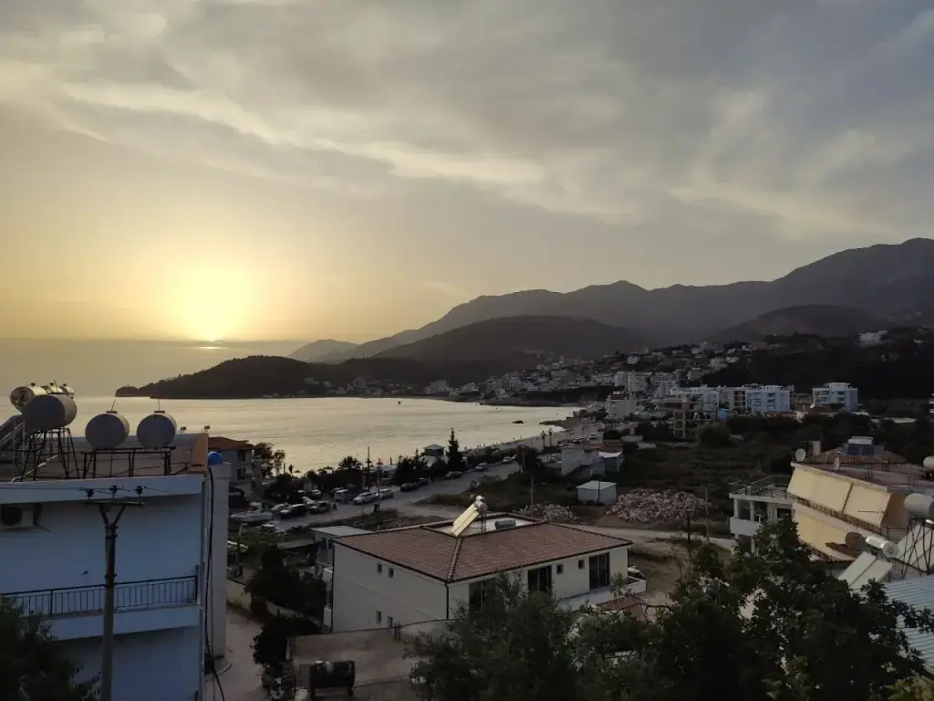 Himarë bay at sunset seen from above, the town along the shore and mountains behind