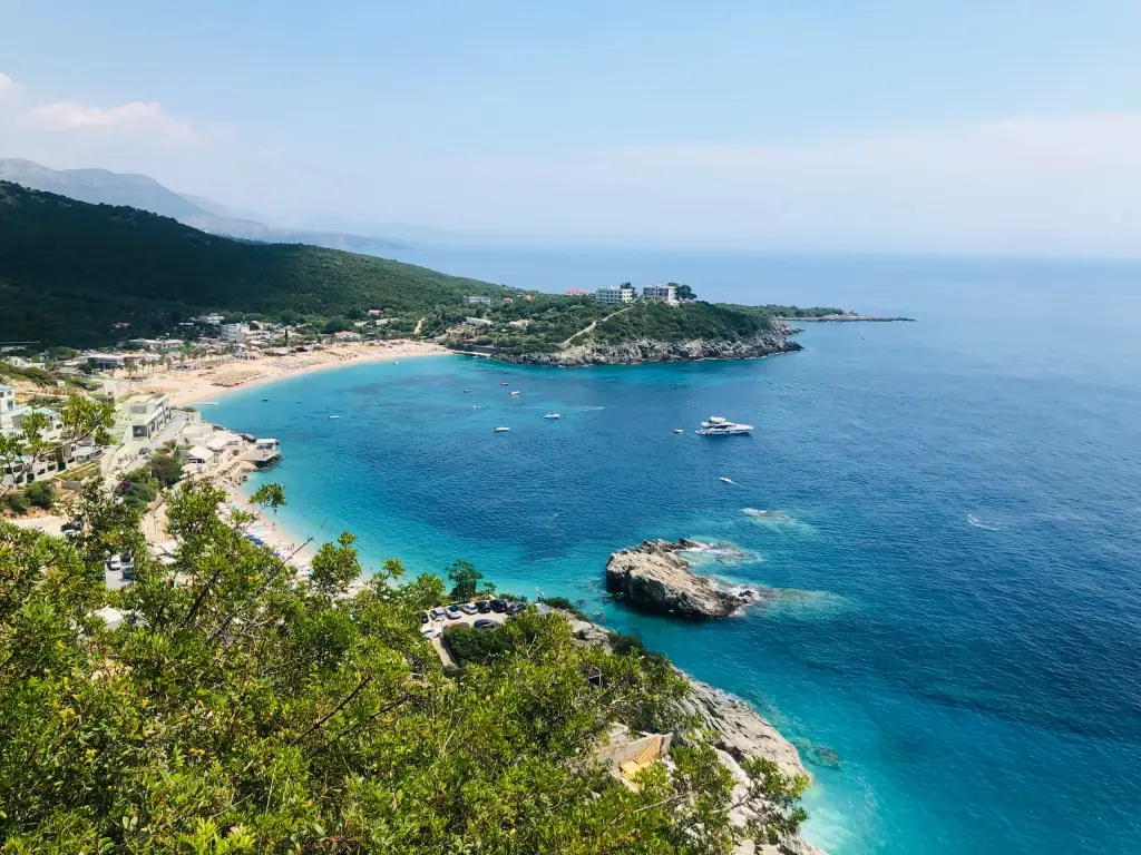 Jalë beach and its headland seen from the hills to the south, with boats anchored in the bay