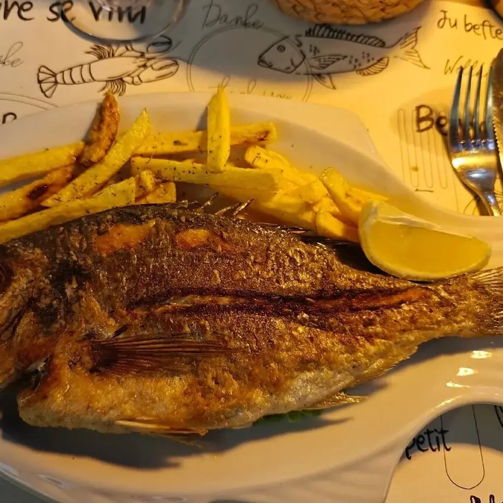 A whole fish, crisp-skinned, with chips and lemon, close