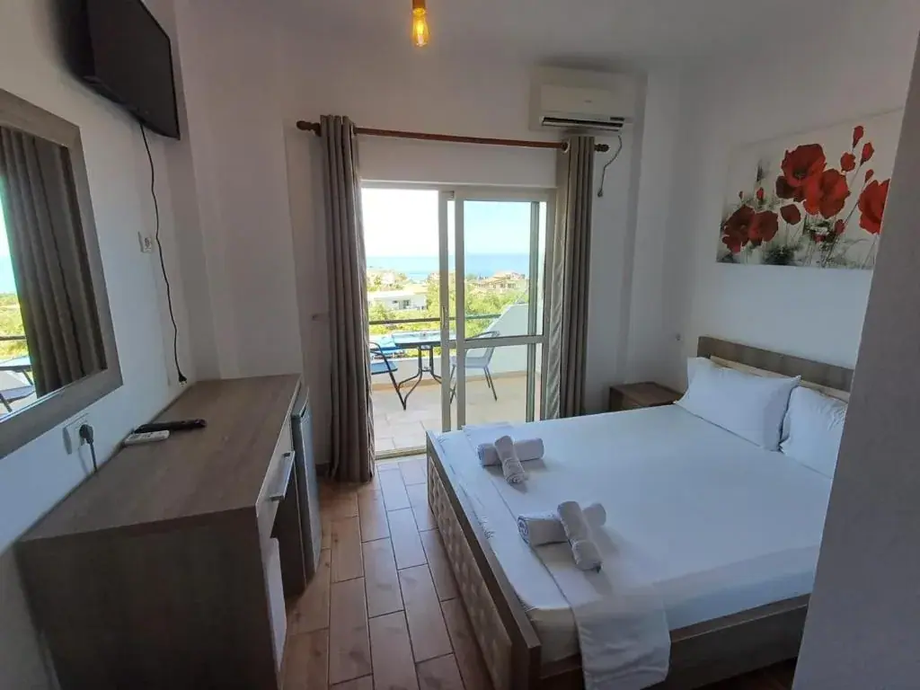 A double room at Velco BB Himara with a balcony door open onto a sea view