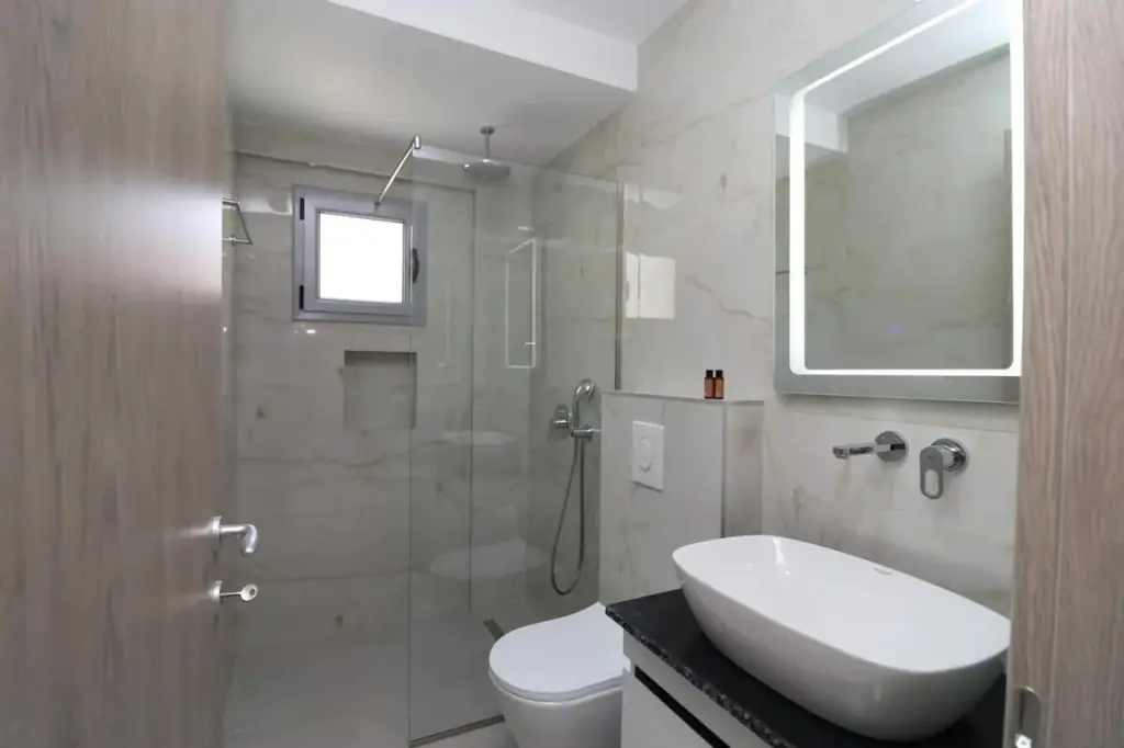 Bathroom with a walk-in glass shower and stone-tiled walls