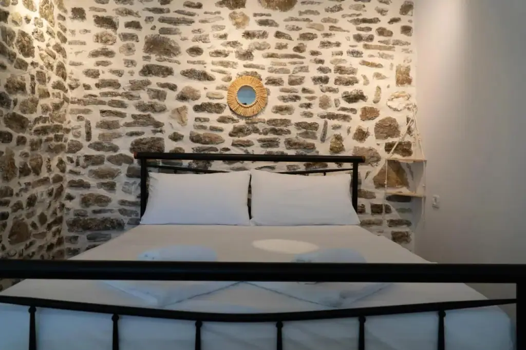 Double room with an iron bed against an exposed stone wall