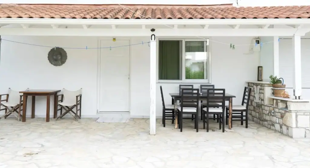 The covered terrace with a long dining table under a tiled roof