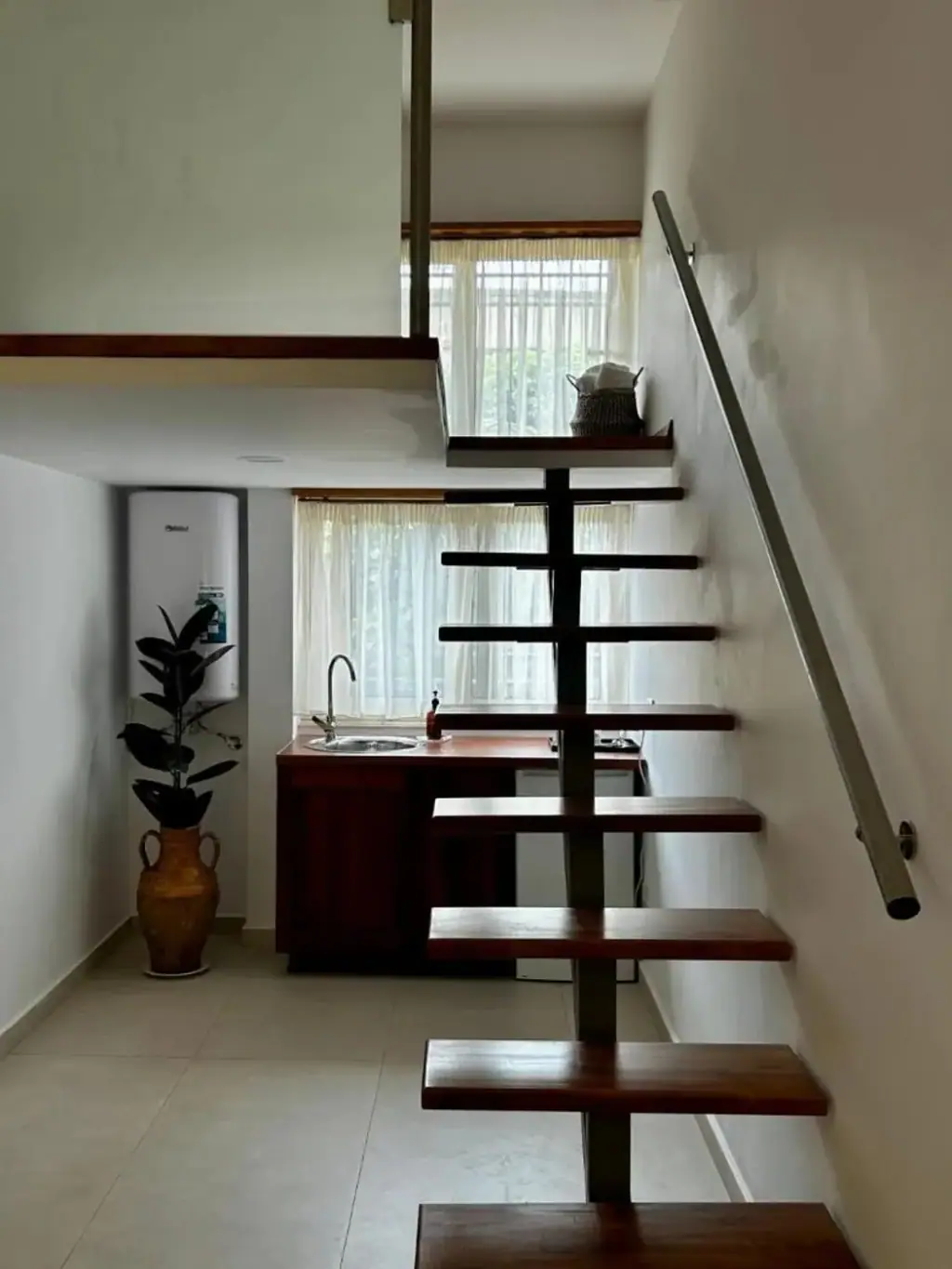 Open wooden stair to a mezzanine above a walnut kitchenette