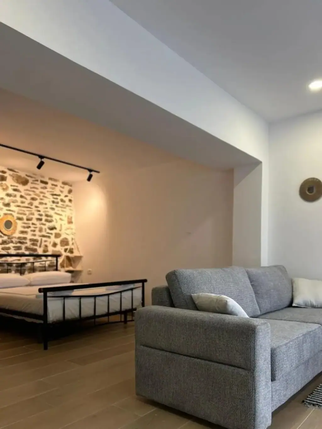 Studio living area with a grey sofa and a stone accent wall