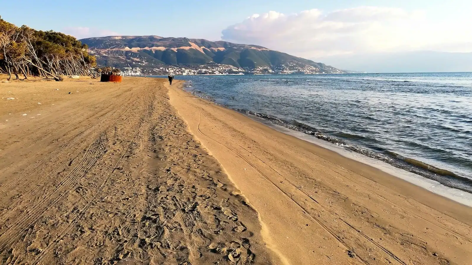 Sunset glow through straw beach umbrellas and sunbeds on the Albanian Riviera coast