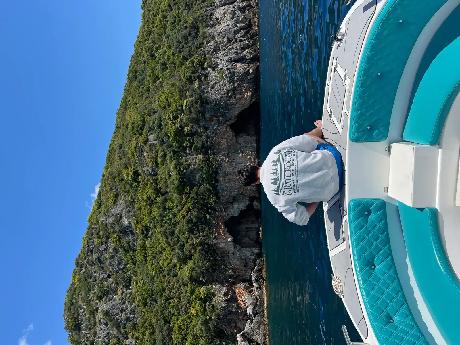 Boat approaching a hidden turquoise cove along the coastline near Himara