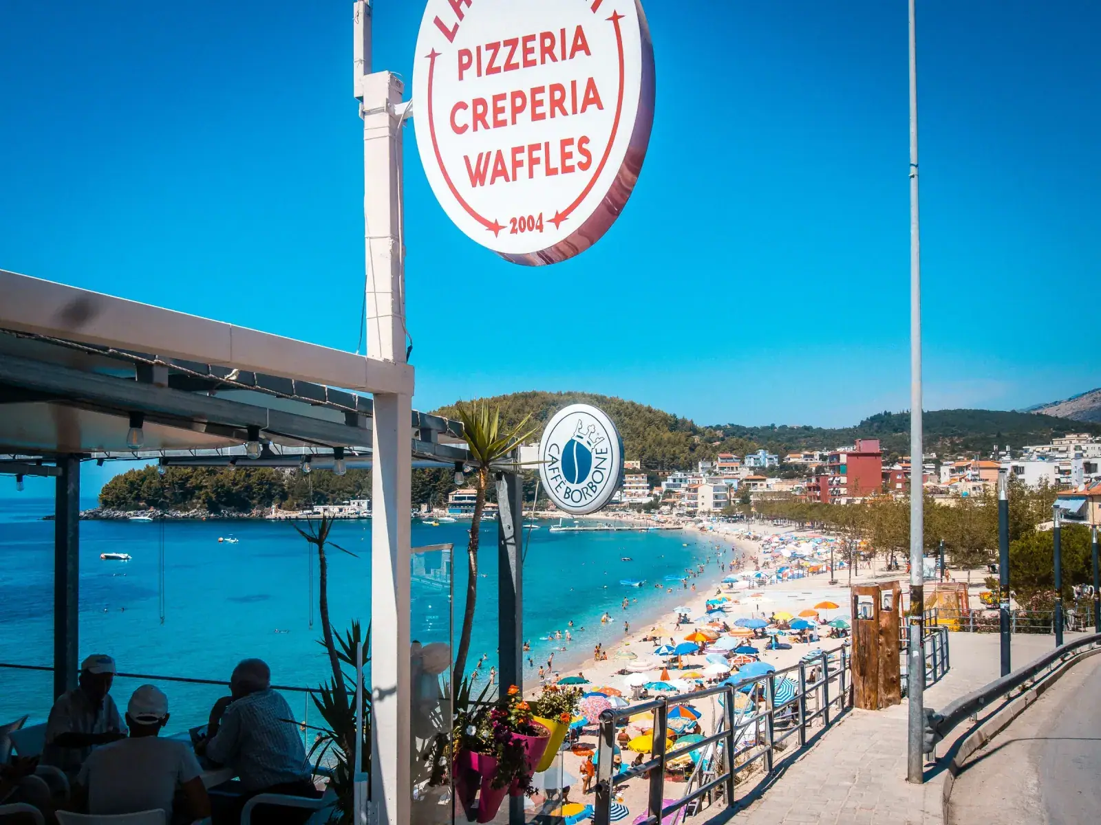 Waterfront dining terrace along Himara Spile promenade with sea views