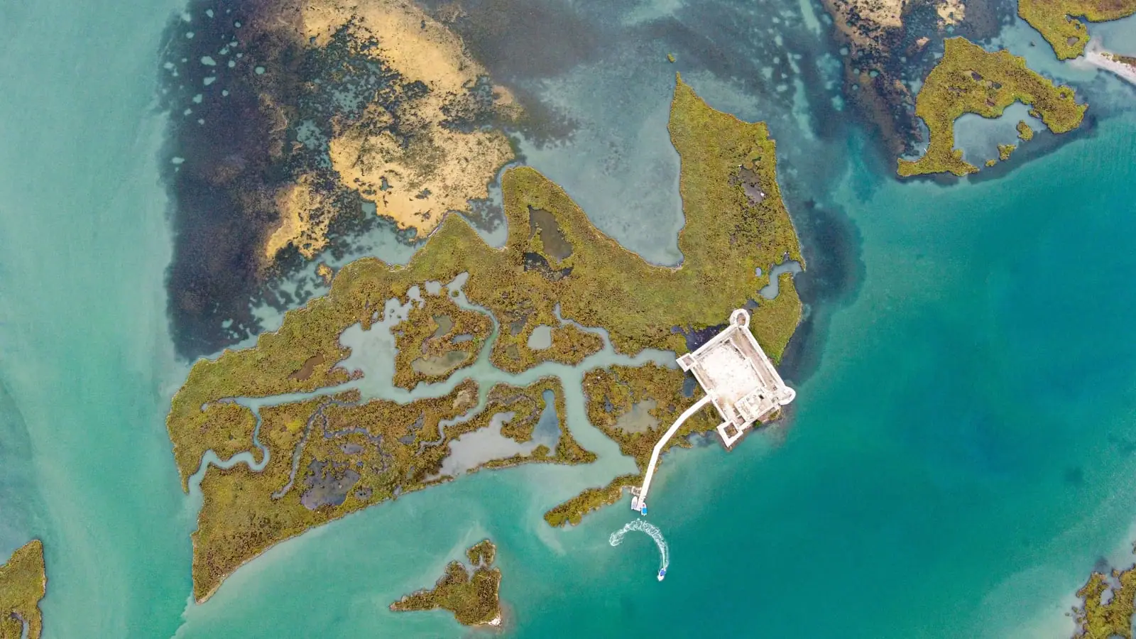 Aerial of a fortified ruin on a marshy lagoon island in the Butrint area near Ksamil, a key day-trip site on a Saranda-Ksamil split stay