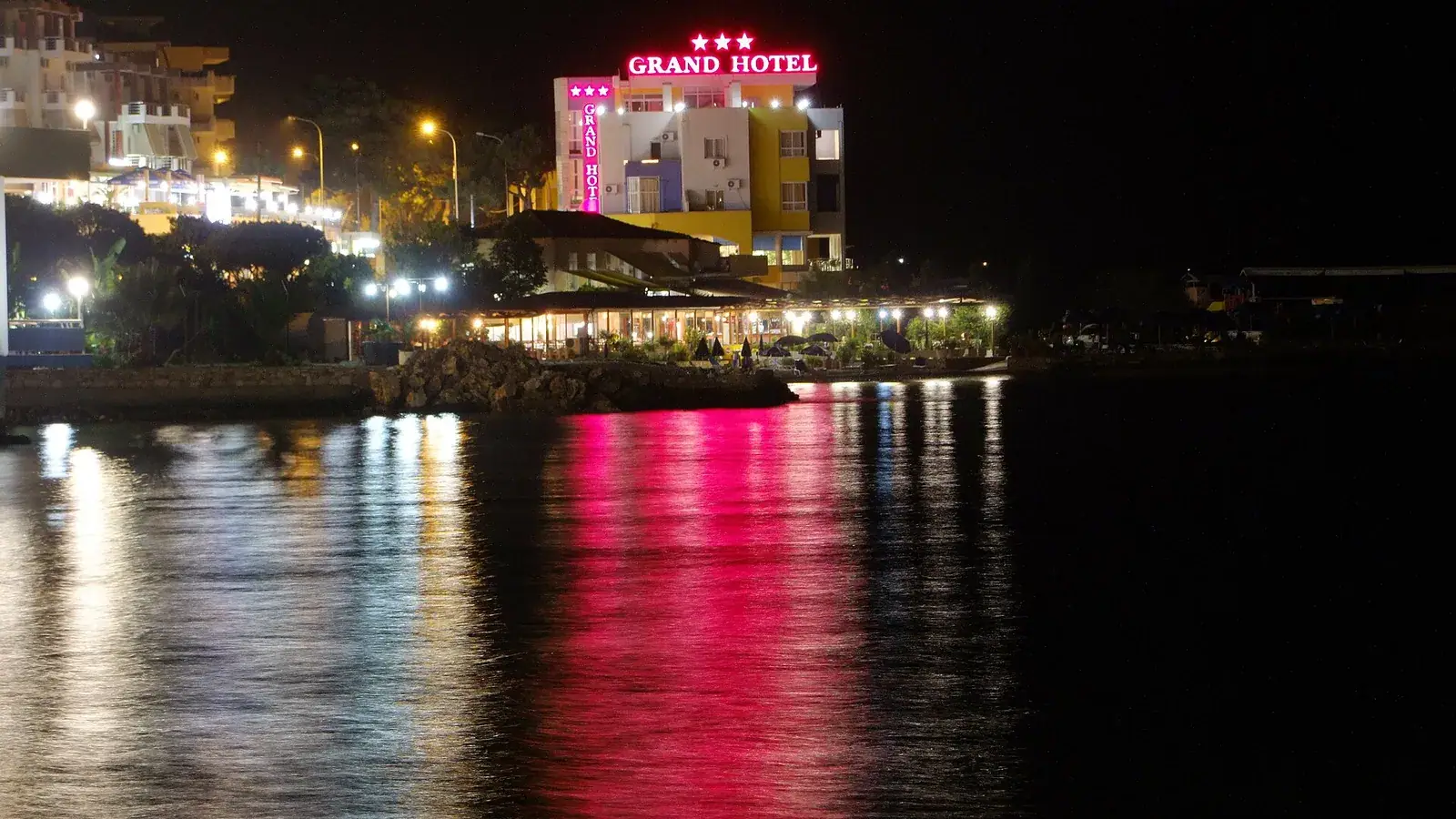 Saranda seafront at night with hotel and restaurant lights reflected in the bay