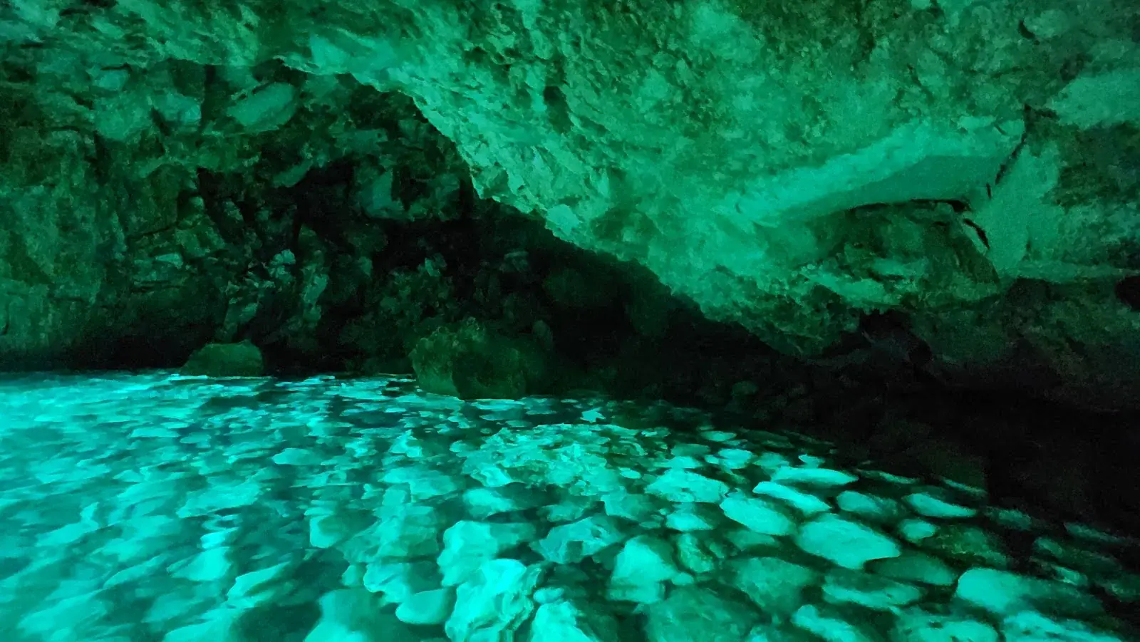 Emerald water over pebbles inside the cave
