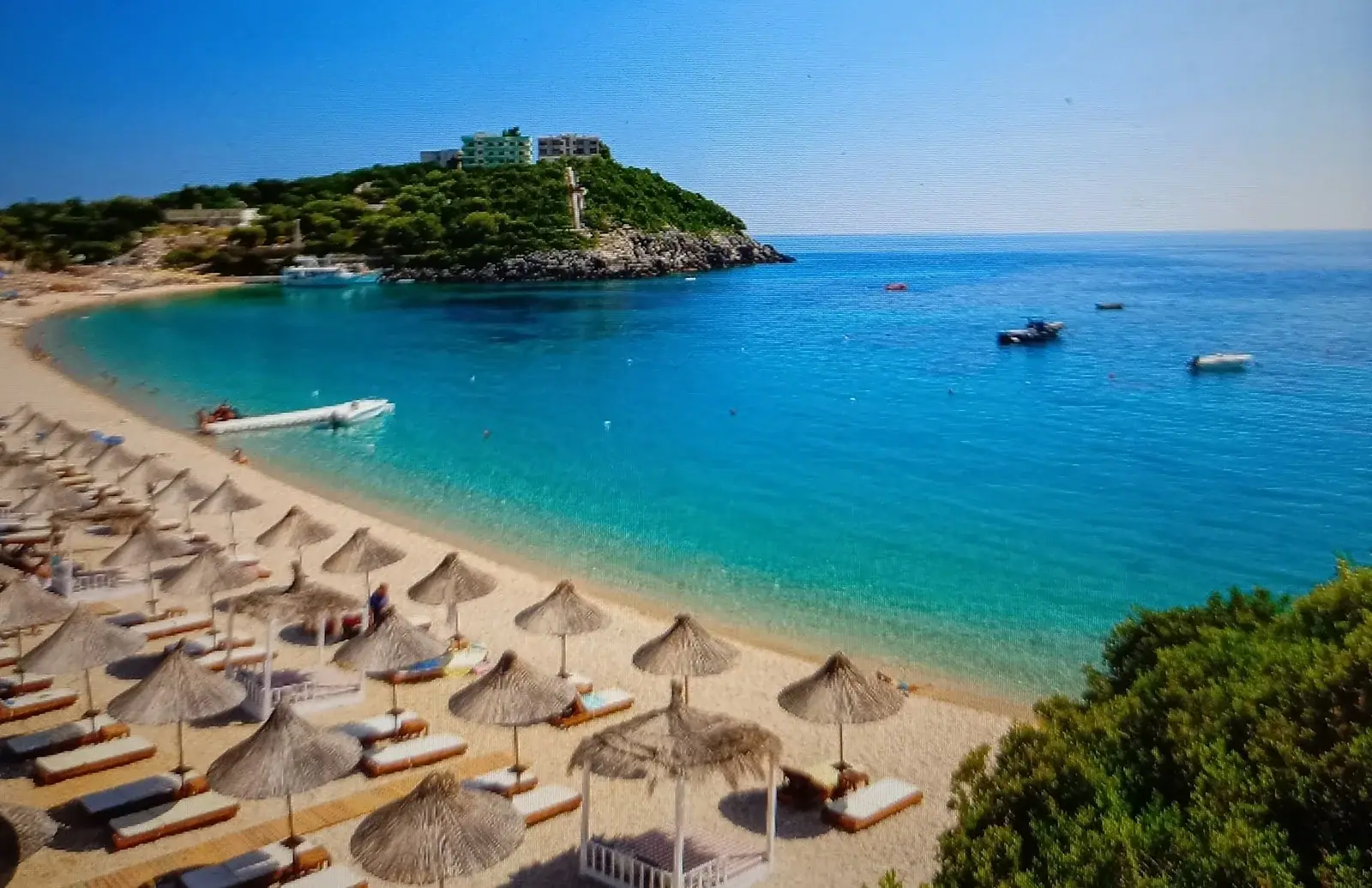 Thatched umbrellas on Jale Beach with the islet offshore