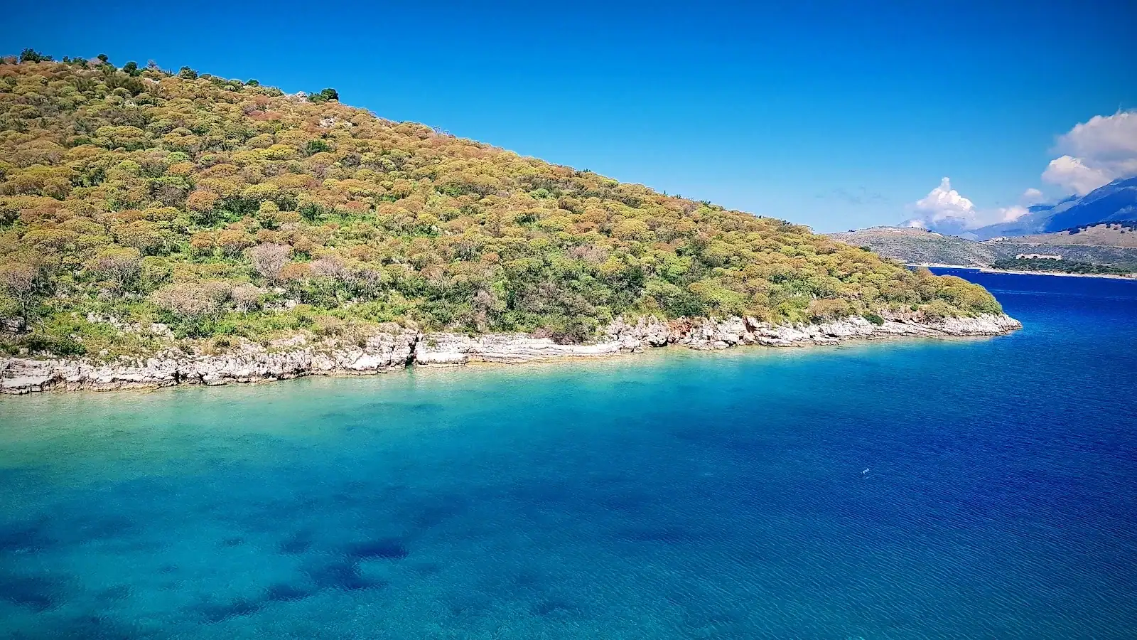 Porto Palermo's bay seen from the slope, deep blue turning turquoise inshore