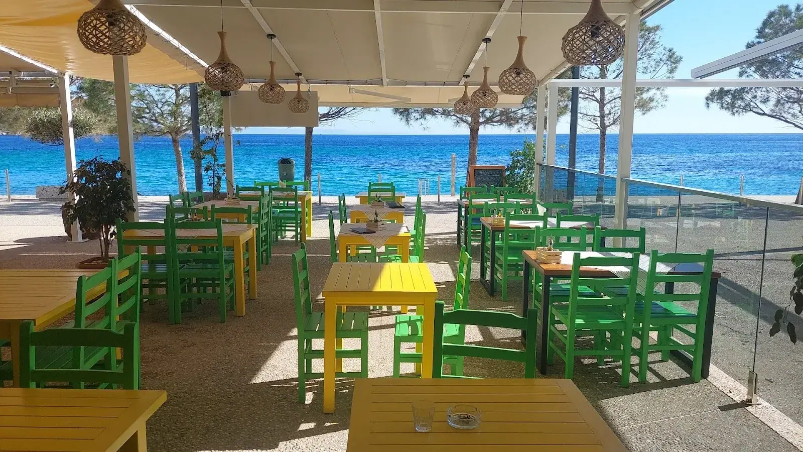 Sea-view terrace with green chairs at Hercules Restaurant in Himara