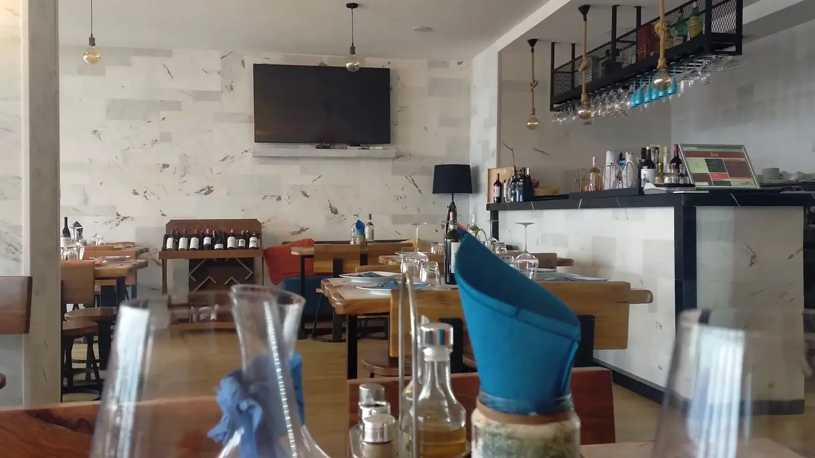 Marble-walled dining room with wooden tables and wine display at Arxontiko Restaurant in Himara