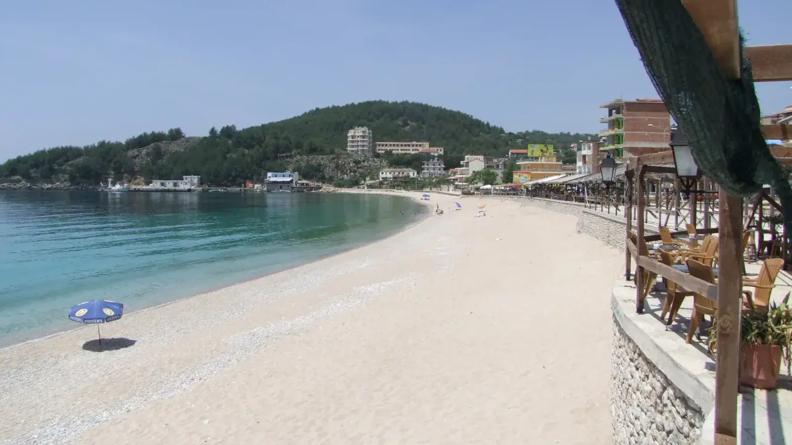 Himara's beachfront, with taverna terraces along the shore and the harbour beyond