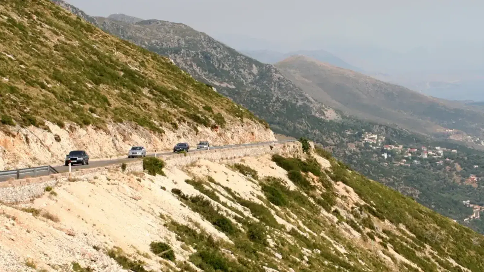 Cars on the cliffside coastal road above Dhermi, the route the intercity buses run