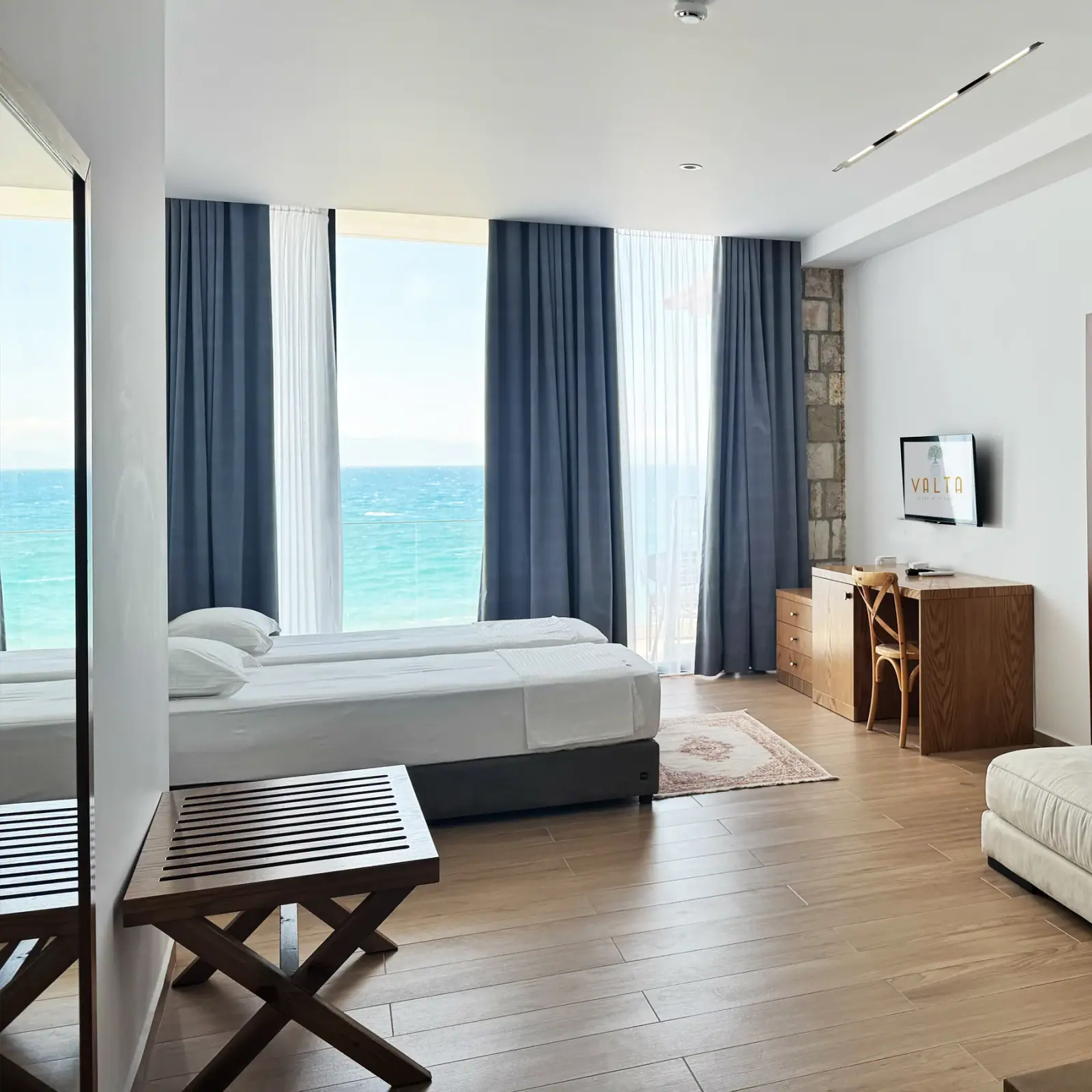 A sleeping area with grey curtains drawn back from a window filled by the bay